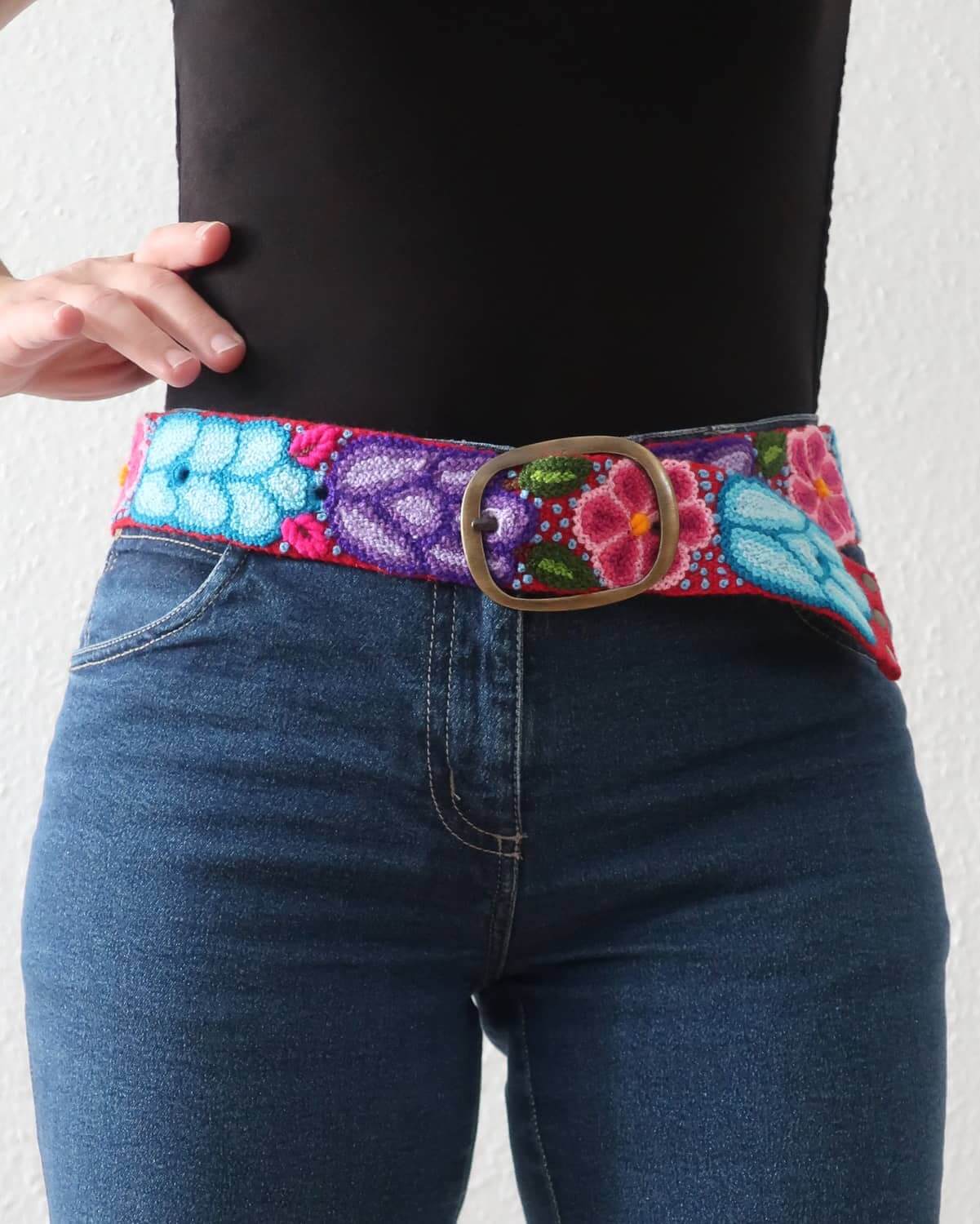 Der bunte, bestickte rote Ayni Pacha Gürtel passt im Alltag perfekt zu einer lässigen Jeans.