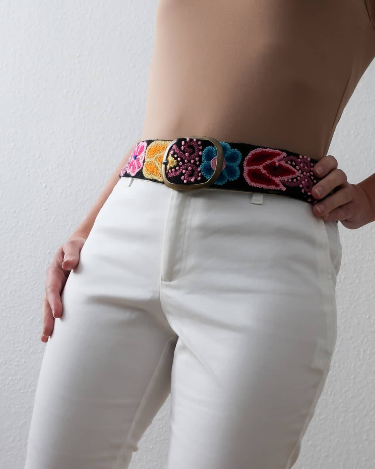 Ayni Ppacha Gürtel Aralia für Damen, in Peru aus Wolle bestickt mit bunten Blumen auf schwarzer Basis, stilvoll kombiniert als elegantes Boho Chic Outfit.