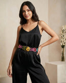 Model trägt den schwarzen, handbestickten Gürtel 'Aralia' aus 100% Schafwolle von Ayni Ppacha als eleganten Taillengürtel über einem schwarzen Satin-Jumpsuit.