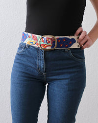 Ayni Ppacha Gürtel Piri Piri für Damen, in Peru aus Wolle bestickt mit bunt abstraktem Design, stilvoll kombiniert zu einer blauen Jeans.
