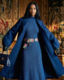 Model trägt den bestickten Gürtel 'Morera' mit Blätter-Muster als farbigen Akzent zu einem dunkelblauen Strickkleid und passendem Wollmantel im eleganten Winter-Look.