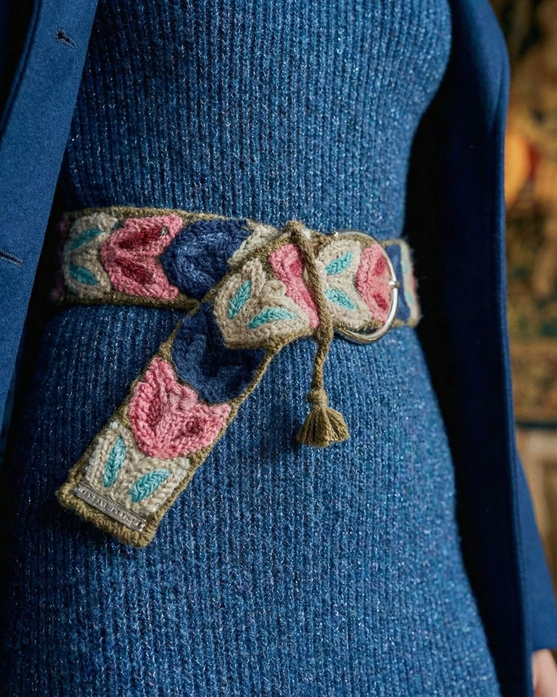 Detailansicht der handbestickten Blätter (Pink, Blau) auf dem olivgrünen Wollgürtel 'Morera', mit Fokus auf die Textur und die dezente, silberne Schnalle.