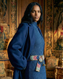 Seitenansicht des Models im blauen Strickkleid mit dem Gürtel 'Morera', die die flexible Passform des Wollmaterials an der Taille zeigt