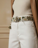 Detailansicht der seitlichen Quaste und der feinen Blatt-Stickerei in Oliv und Brauntönen auf dem wollweißen Wollstoff des Gürtels 'Nolina'.