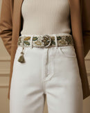 Frontalansicht des Gürtels 'Nolina', der perfekt durch die Schlaufen einer weißen Jeans passt, mit Fokus auf die ovale, silberfarbene Metallschnalle und das organische, florale Muster.