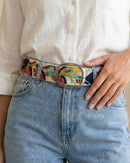 Nahaufnahme der Textur des wollweißen Ayni Ppacha Gürtels 'Piri Piri' aus 100% Schafwolle, kombiniert zu einer hellblauen Jeans, mit Fokus auf die feine Stickerei und die silberne Schnalle.